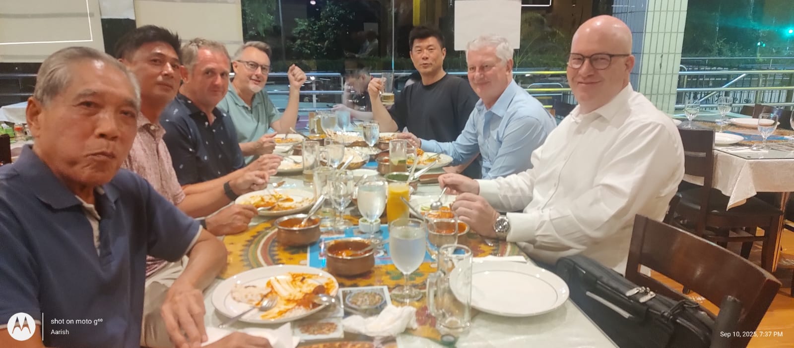 Guests sharing curries and biryani around a long dinner table